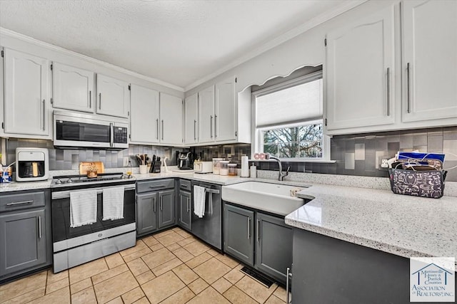 kitchen with crown molding, tasteful backsplash, gray cabinetry, a sink, and stainless steel appliances