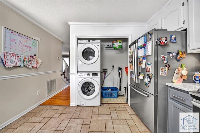 laundry area featuring ornamental molding, stacked washer / drying machine, laundry area, and visible vents