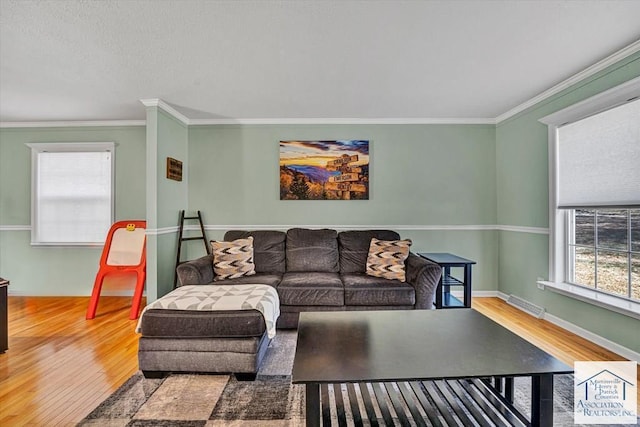 living room with crown molding, baseboards, wood finished floors, and visible vents