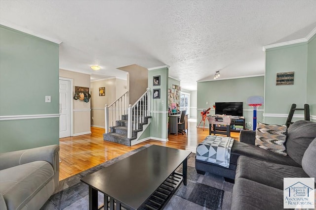 living room featuring crown molding, baseboards, wood finished floors, and stairway