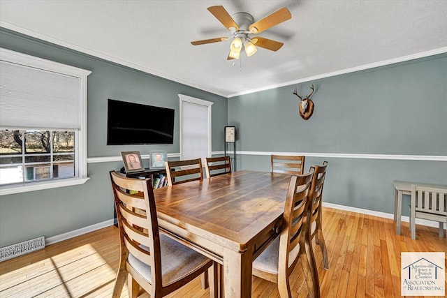 dining space featuring wood-type flooring, crown molding, visible vents, baseboards, and ceiling fan