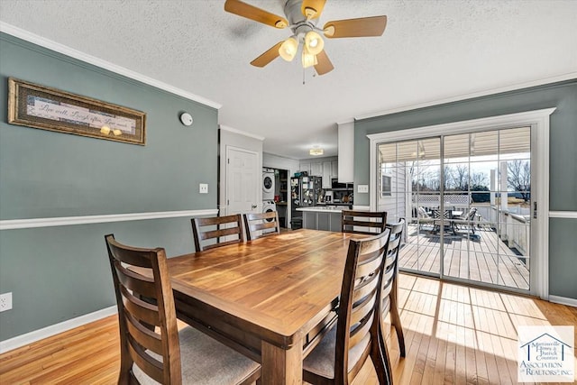 dining space with stacked washer and clothes dryer, ornamental molding, a textured ceiling, a ceiling fan, and light wood-style flooring