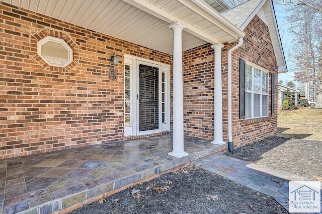 property entrance with covered porch and brick siding