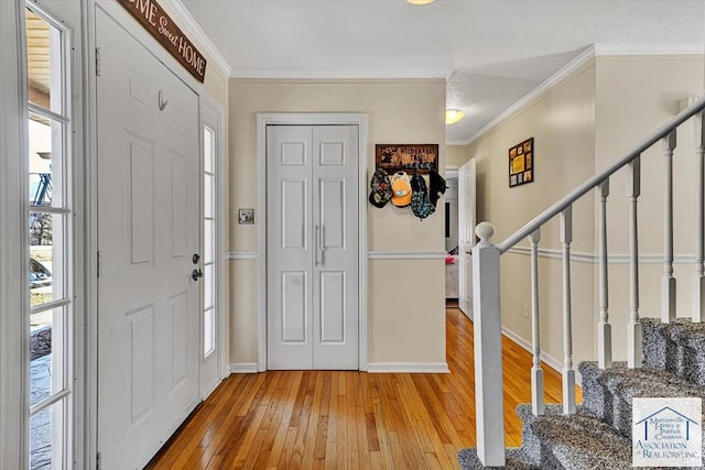 entryway with baseboards, ornamental molding, stairway, and light wood-type flooring