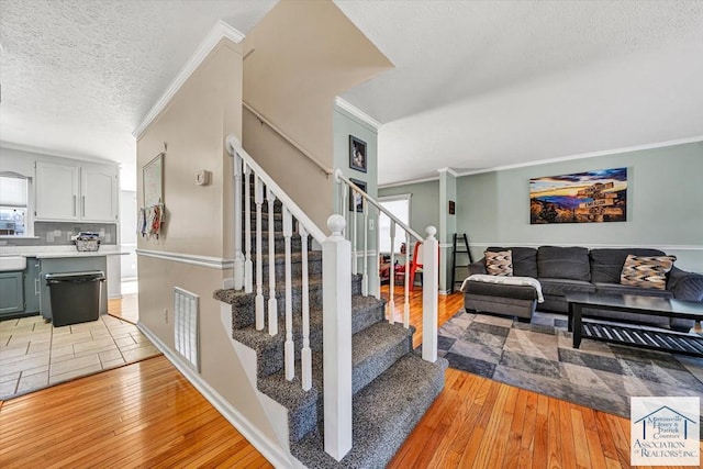 staircase featuring ornamental molding, a textured ceiling, and hardwood / wood-style floors