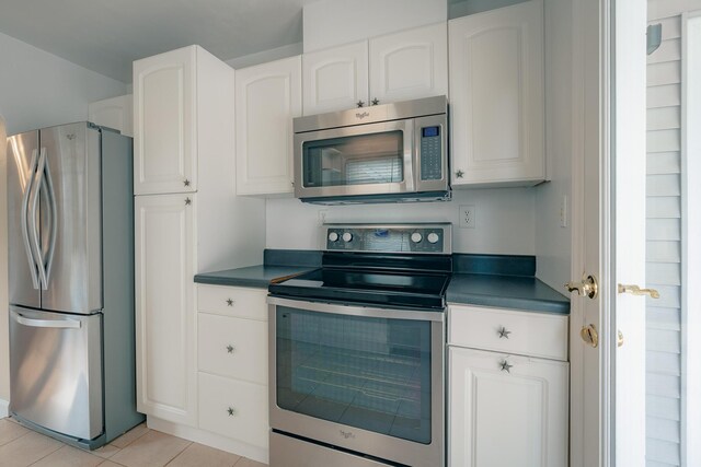 2509 Sweetbrier Ave SW, Roanoke, VA 24015 - kitchen featuring white cabinetry, dark countertops, appliances with stainless steel finishes, and light tile patterned floors