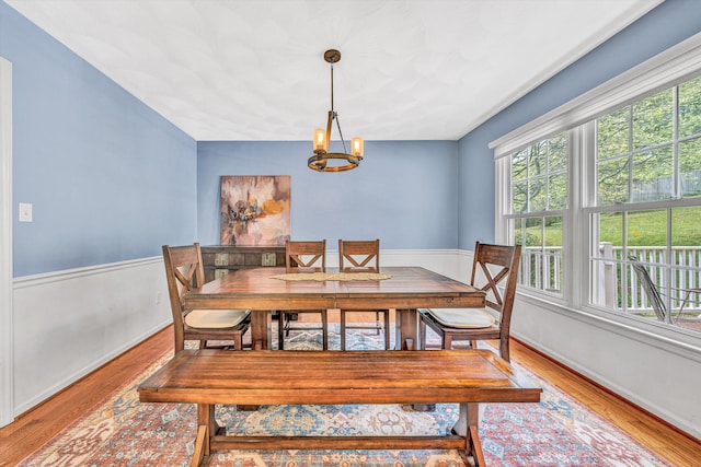 dining room with plenty of natural light, wood finished floors, a chandelier, and a wainscoted wall