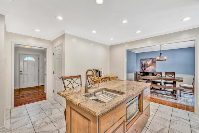 kitchen featuring a sink, light marble finish floors, stainless steel microwave, recessed lighting, and crown molding