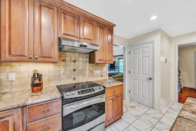 kitchen featuring stainless steel electric range, under cabinet range hood, light stone countertops, brown cabinets, and crown molding