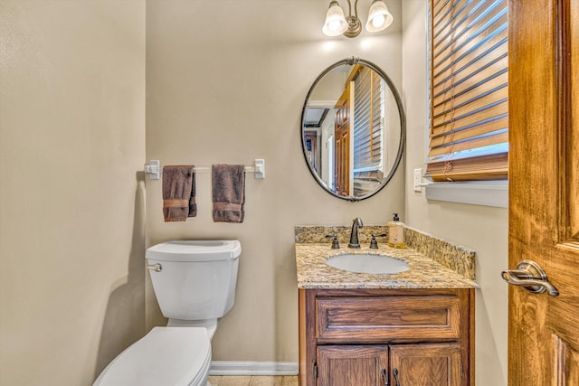 bathroom with toilet, vanity, and baseboards