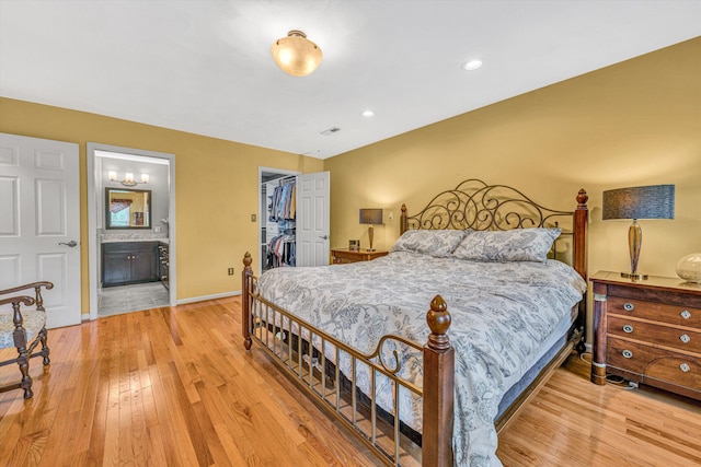 bedroom featuring light wood-style flooring, a spacious closet, connected bathroom, a closet, and recessed lighting