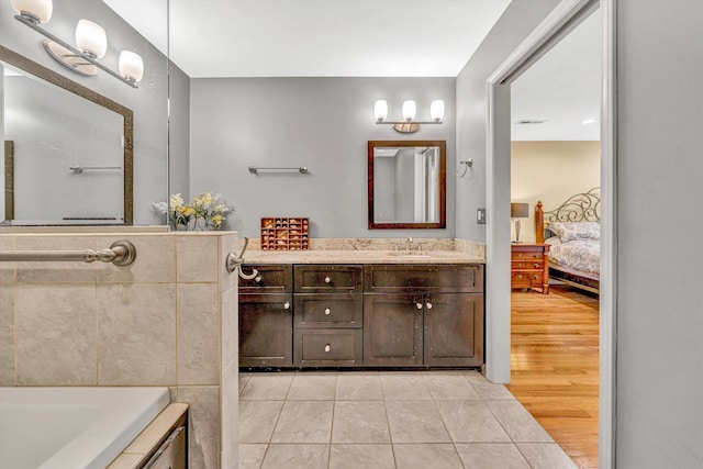 full bathroom featuring ensuite bath, vanity, tile patterned flooring, and a tub