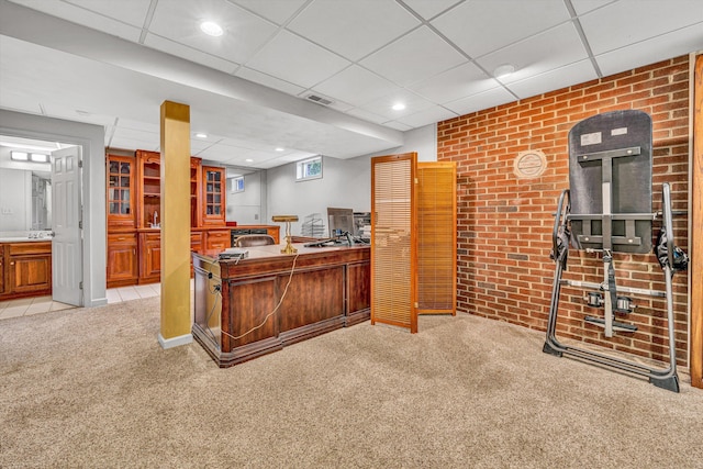 office area with light carpet, a paneled ceiling, and brick wall