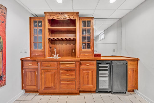 indoor wet bar with a drop ceiling, baseboards, light tile patterned flooring, and wine cooler