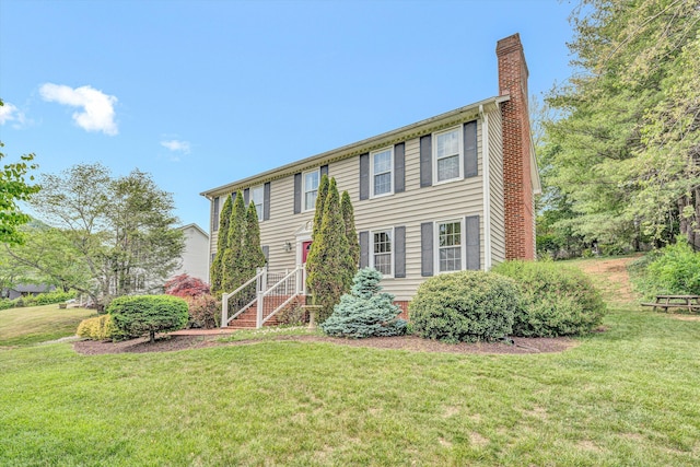 colonial home featuring a chimney and a front yard