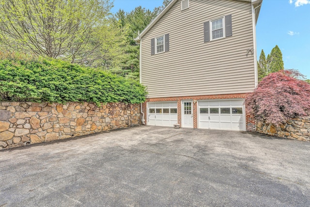 view of side of property with a garage, driveway, and brick siding