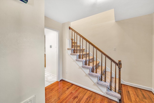 staircase featuring baseboards and wood finished floors