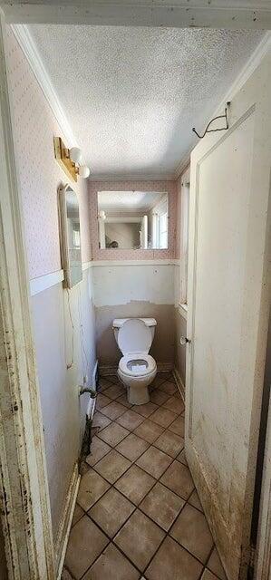 bathroom featuring crown molding, a textured ceiling, tile patterned floors, and toilet