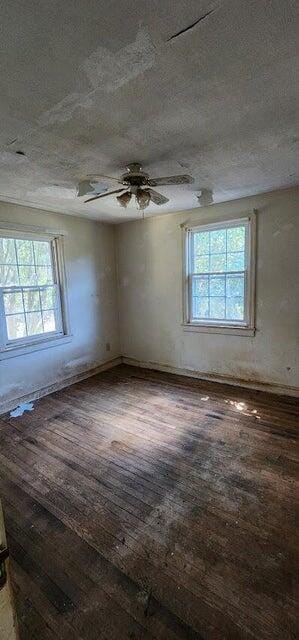 spare room with wood-type flooring, a ceiling fan, a textured ceiling, and a healthy amount of sunlight