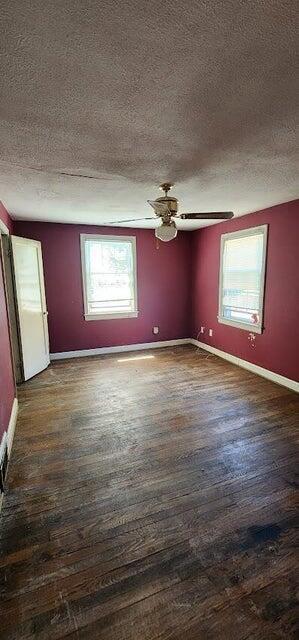 unfurnished room with baseboards, dark wood finished floors, and a textured ceiling