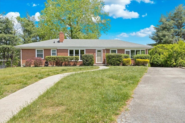 ranch-style house with brick siding, a chimney, and a front lawn