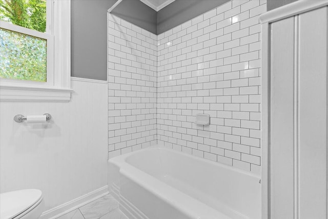 full bathroom featuring toilet, shower / bath combination, marble finish floor, and a wainscoted wall