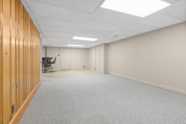 finished basement with wooden walls, baseboards, and carpet flooring