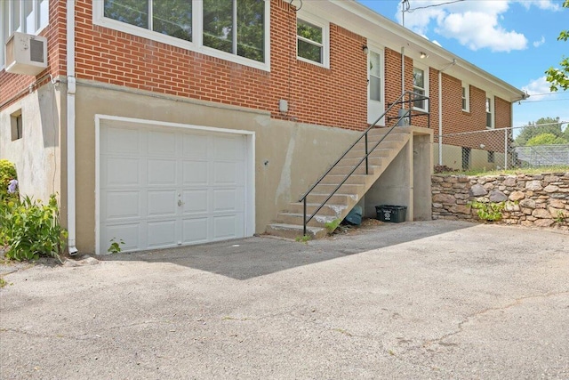 exterior space with brick siding, an attached garage, and stairs