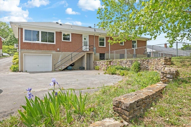 view of front facade featuring brick siding, an attached garage, fence, and aphalt driveway