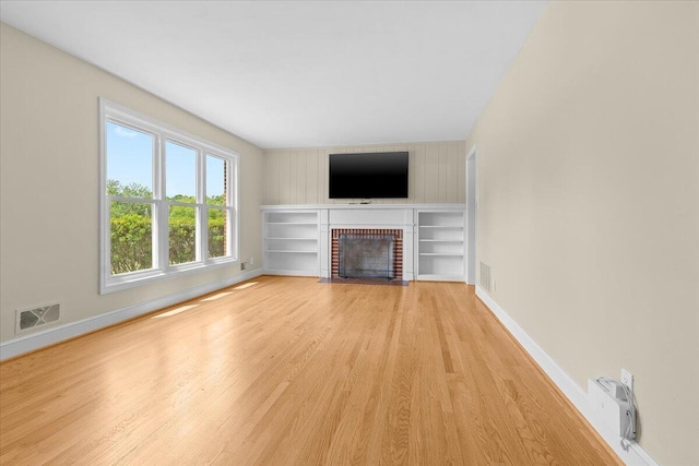 unfurnished living room with a brick fireplace, baseboards, visible vents, and light wood-type flooring