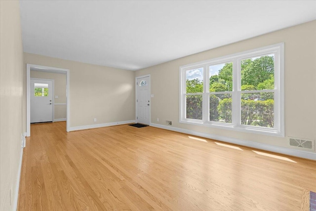 unfurnished living room with baseboards, light wood-style flooring, and visible vents
