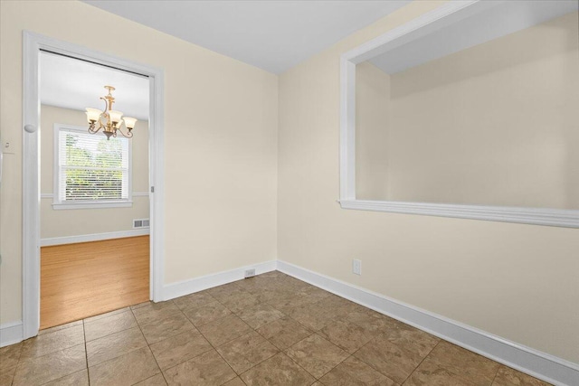 unfurnished room featuring baseboards, a chandelier, and visible vents