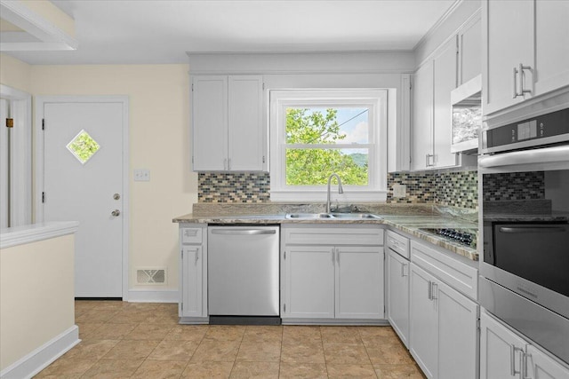 kitchen featuring visible vents, white cabinetry, tasteful backsplash, a sink, and stainless steel appliances