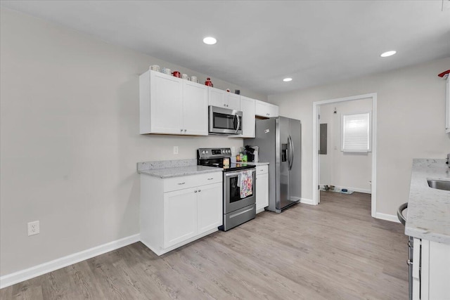 kitchen with white cabinets, baseboards, appliances with stainless steel finishes, and light wood finished floors