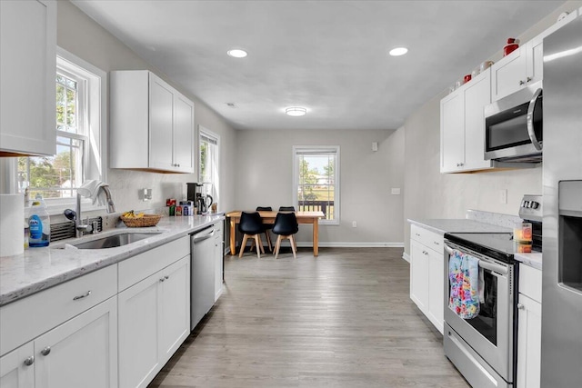 kitchen with light wood-style floors, a sink, recessed lighting, and stainless steel appliances