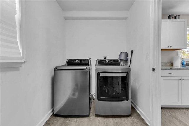 washroom featuring washer and dryer, laundry area, baseboards, and light wood-style floors