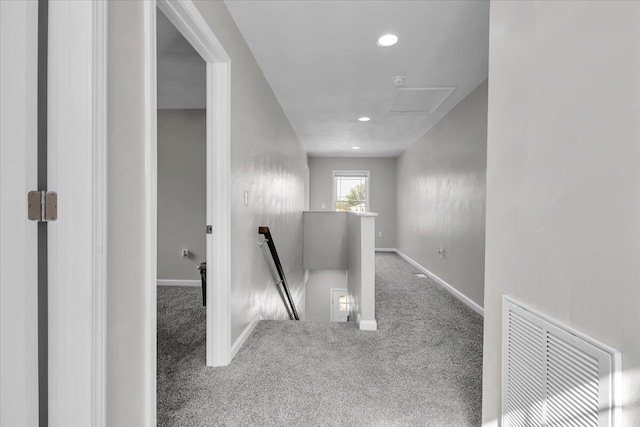corridor with visible vents, baseboards, attic access, carpet, and an upstairs landing