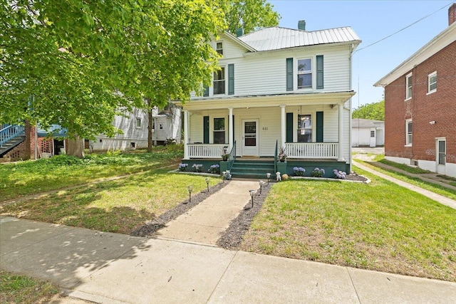 view of front of property with a porch, a front yard, and metal roof