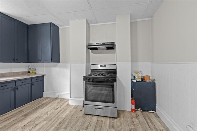kitchen featuring light wood-style floors, blue cabinets, under cabinet range hood, and gas stove