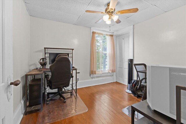 office with a ceiling fan, a drop ceiling, and hardwood / wood-style flooring