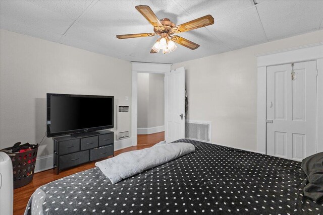 bedroom with a ceiling fan, baseboards, visible vents, and wood finished floors