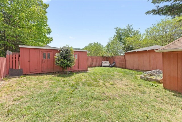 view of yard featuring a storage unit, a fenced backyard, and an outdoor structure