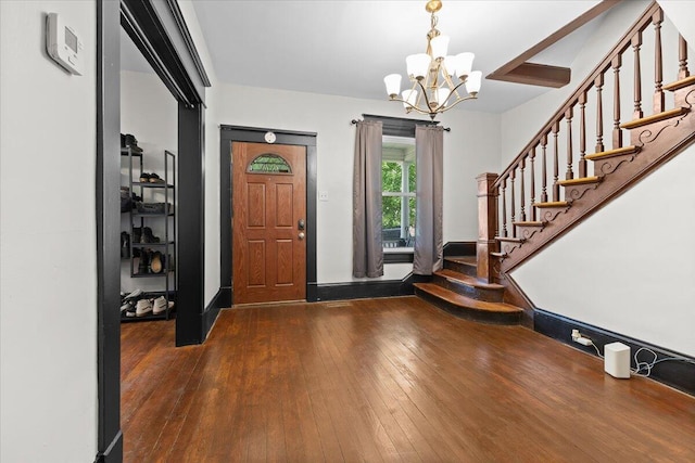 foyer entrance with dark wood-type flooring, stairs, and a notable chandelier