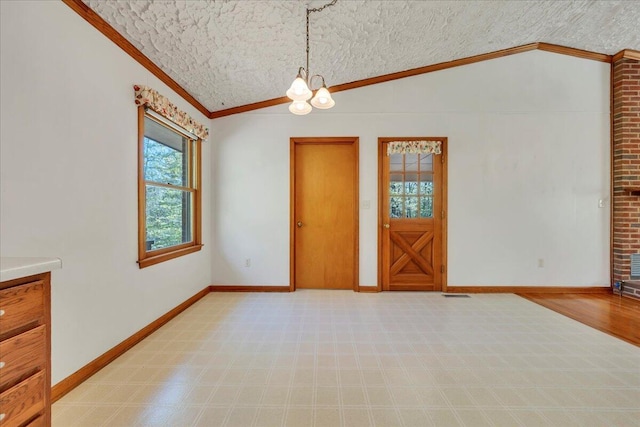empty room featuring ornamental molding, a textured ceiling, lofted ceiling, and a notable chandelier