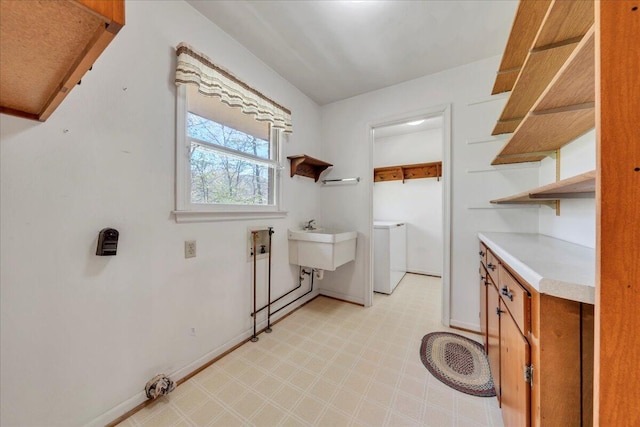 washroom featuring cabinet space, baseboards, washer and clothes dryer, and light floors