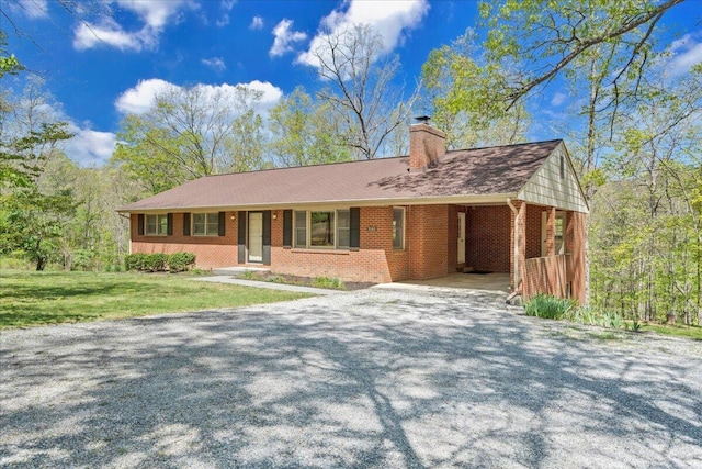 ranch-style house with a chimney, a front yard, driveway, and brick siding