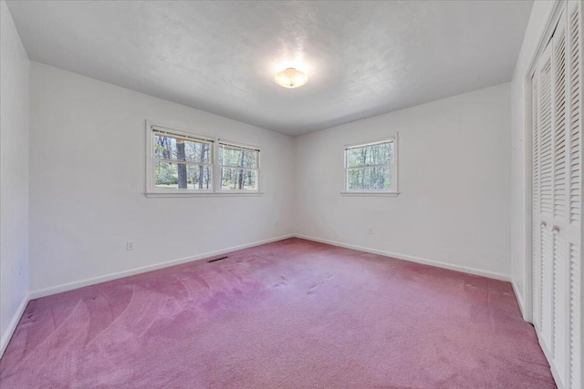 unfurnished bedroom featuring baseboards, carpet flooring, visible vents, and a closet