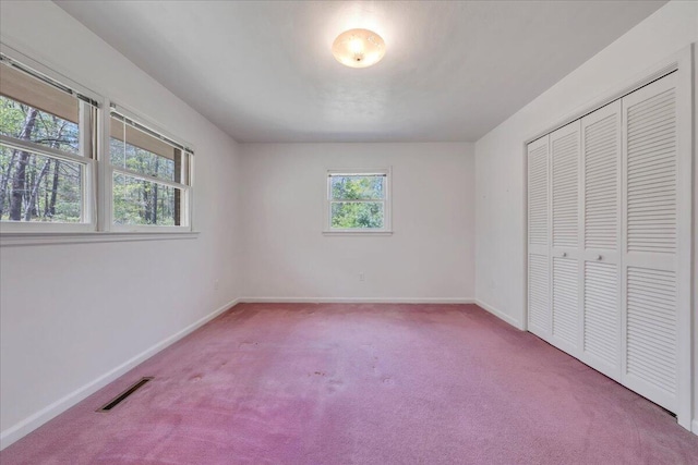 unfurnished bedroom with a closet, baseboards, carpet flooring, and visible vents