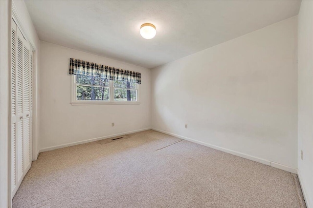 unfurnished bedroom with baseboards, light colored carpet, and a closet