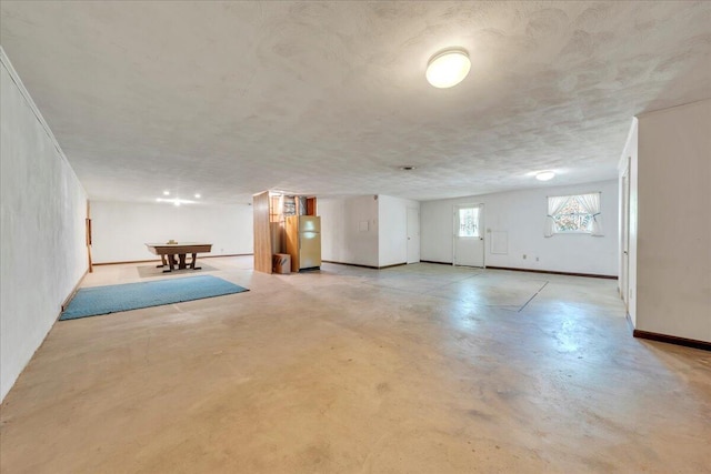 basement featuring baseboards, freestanding refrigerator, and billiards